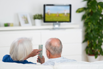 senioren-ehepaar mit fernbedienung vor dem tv