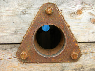 Triangular rusty metal spare part fastened at a wooden surface