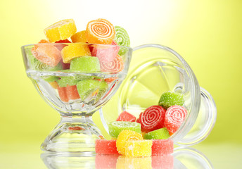 colorful jelly candies in  in glass bowls on green background.