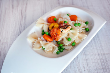 Pasta salad and three kinds of prawn on wooden table