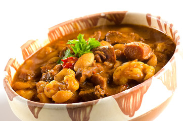 Goulash in clay pot against white background