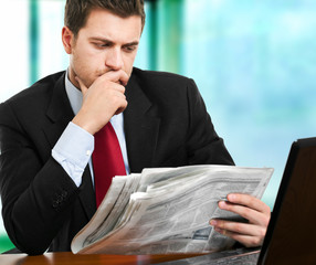 Businessman reading a newspaper at his desk