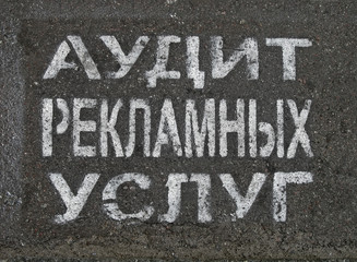 advertising service audit as painted text on russian on asphalt,