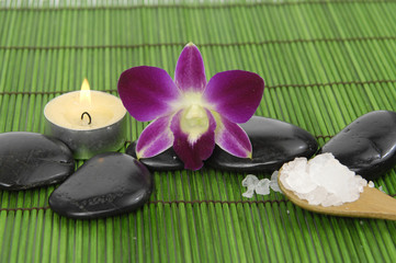 Fototapeta na wymiar orchid, candle with zen stone and sea salt in spoon on mat