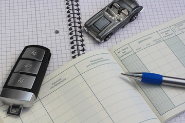 Büromaterial mit Fahrtenbuch und einem Auto