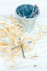 Ведро с гвоздями и стружка на старом деревянном фоне