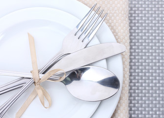 White empty plates with fork, spoon and knife tied with a