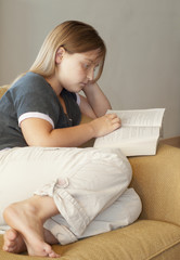 Young girl reading a book on a couch