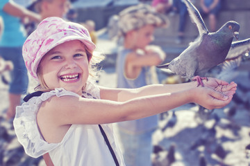 Smiling girl feeding pigeon