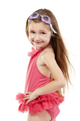 Little girl in pink bathing suit and swimming goggles stands