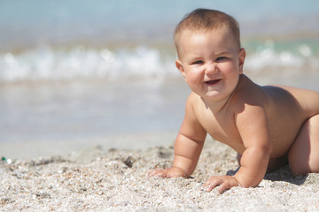 Fototapeta na wymiar outdoor portrait of smiling baby on beach on sea background