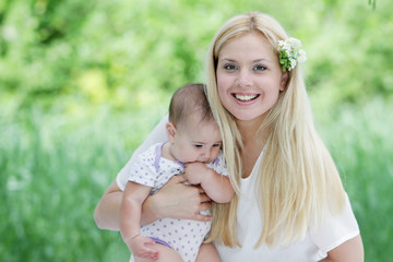 young happy mother and baby on natural background