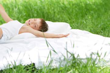 young happy child boy relaxing on natural background