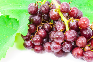 Red grapes with fresh leaves, isolated on white background.