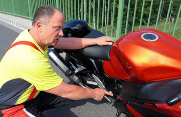 Motorradfahrer erklärt technisches Detail am Motorrad