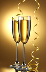 glasses of champagne and streamer on yellow background