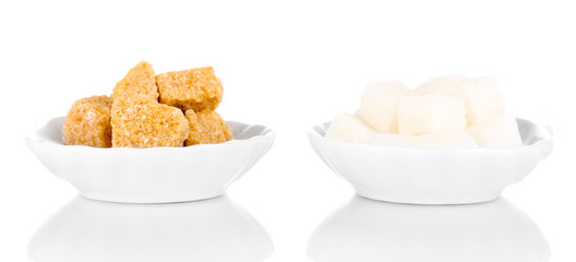 Brown and white sugar cubes in saucers isolated on white