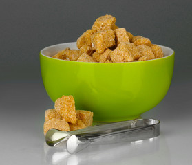 brown cane sugar cubes in bowl with sugar-tongs