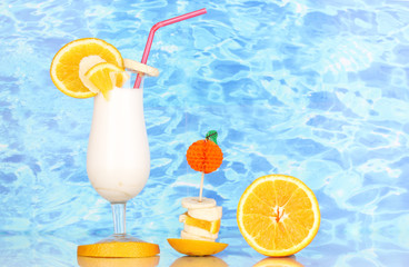Delicious milk shake with fruit on table on blue sea background