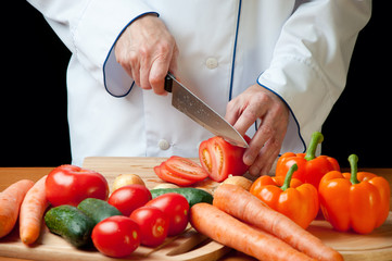 Chef's hands cutting a fresh tomato, horizontal shot