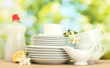 Obraz na płótnie Canvas empty clean plates and cups with dishwashing liquid, flowers