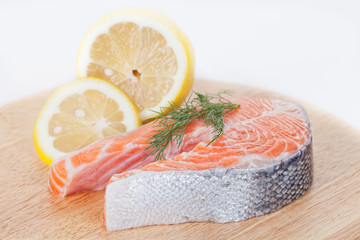 Stake from a salmon with a lemon on a chopping board