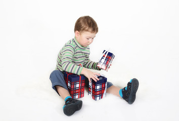 boy sits and plays with gift boxes