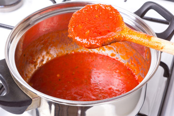 Wooden spoon in the pot with red sauce