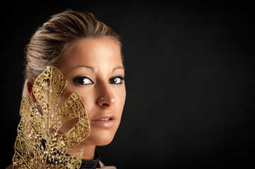 Beautiful woman with golden make up against black background.