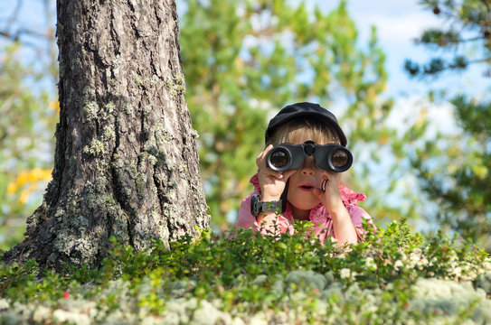 Little girl looking through binoculars with a surprised face