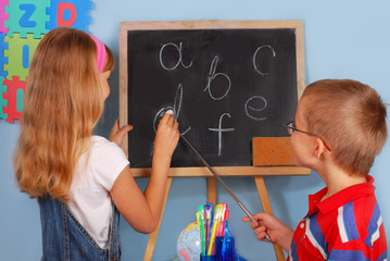 schoolgirl  and schoolboy writing on blackboard