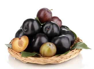Rip plums on wicker cradle isolated on white