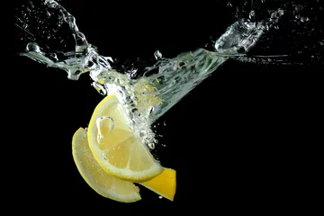 Foto op Plexiglas anti-reflex Gesneden citroen in het water op zwarte achtergrond © Africa Studio