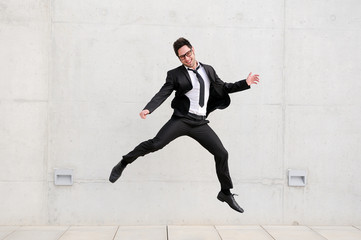 Young handsome businessman with eyeglasses jumping in the street