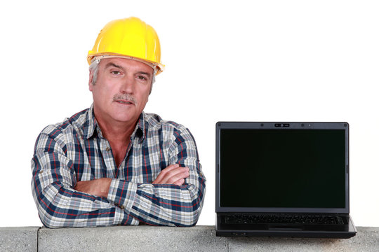 Artisan resting on concrete wall with computer