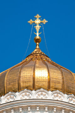 Golden cross of the Orthodox church on the blue sky background