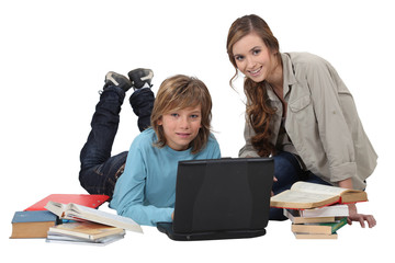 Fototapeta na wymiar teenager doing his homework with laptop and elder sister