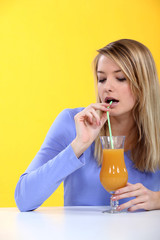 woman drinking orange juice with a straw