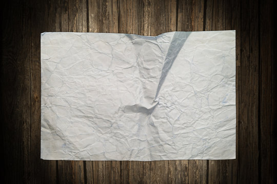Old damaged paper sheet on a wooden background