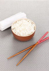 Bowl of rice and chopsticks on grey mat