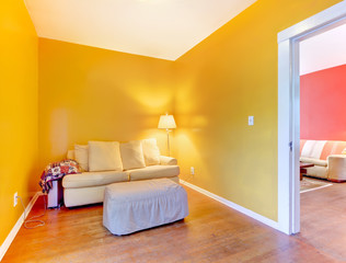 Orange and pink rooms with sofas and hardwood floor.