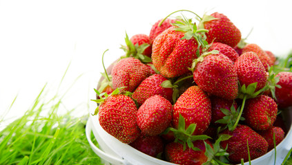 Ripe strawberry in bucket on grass