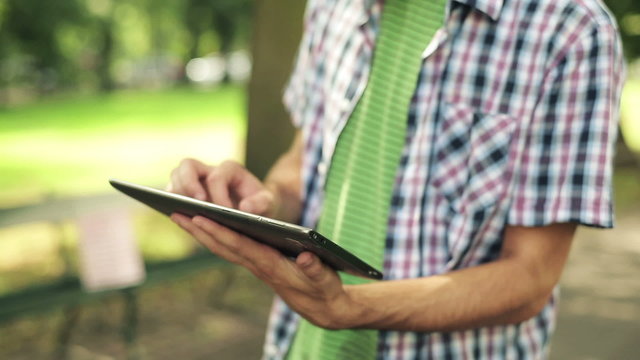 Young man with tablet computer in park, steadicam shot