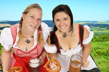 Two young pretty women in dirndl with beer mug in nature