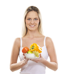 A young blond woman holding a bowl of fresh vegetables