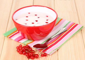 Yogurt with redcurrant on wooden table