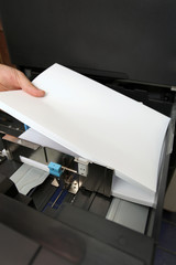 details of hand inserts a paper A4 into a laser copier