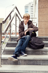 Serious boy sitting on stairs. outdoor