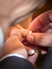 Groom putting wedding ring on bride finger