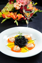 Black pasta with meat, garnished with sauce and  herbs close-up